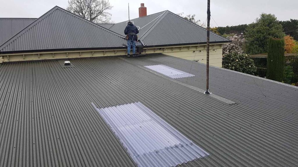 Roofing contractor inspecting a residential long-run metal roof in Christchurch