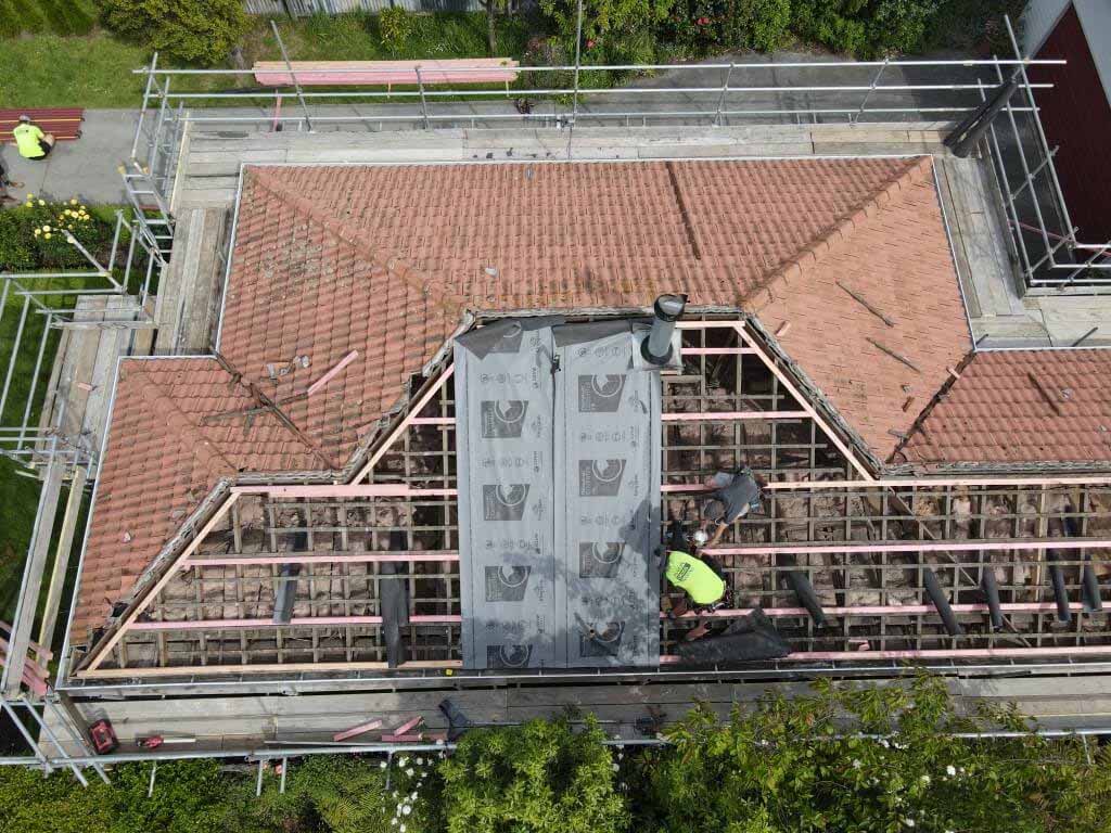 Concrete tile roof replacement in progress on a Christchurch home, showing removed tiles and exposed roof structure during re-roofing work