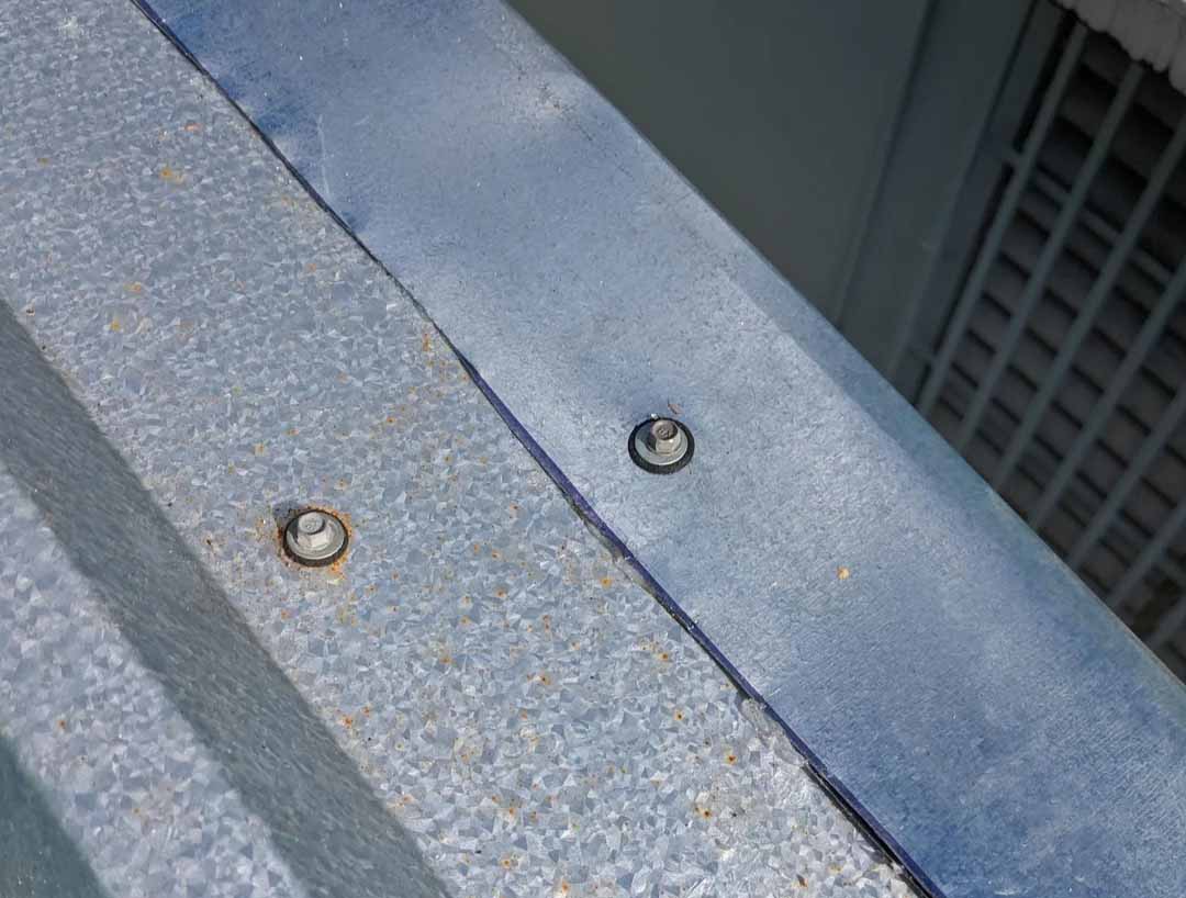 Early rust and corrosion forming around metal roof fixings, showing a common warning sign of deterioration on metal roofing